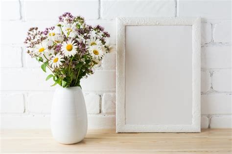 Download White frame mockup with blooming wildflower bouquet near painted brick
